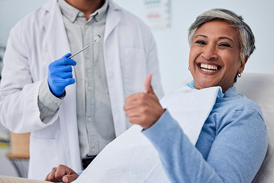 Smiling woman giving thumbs up at dental appointment