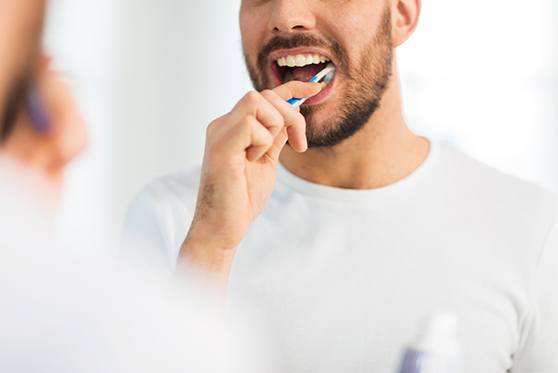 Man in white shirt brushing his teeth