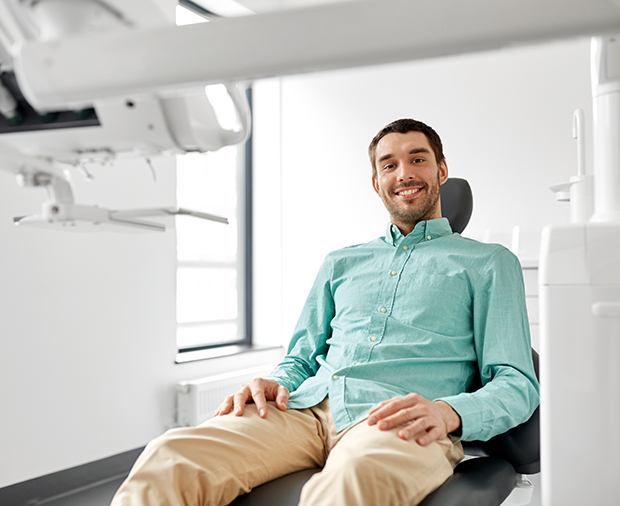 Woman in white shirt sitting in dental chair and smiling