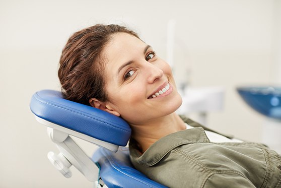 Man in green button-up shirt smiling in dental chair 